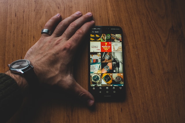 Ruka preko telefona na drvenom stolu sa sveskom